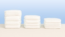 Three stacks of diapers on a white table.
