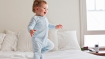 Toddler walking on a light blue carpet.