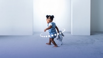 Toddler walking on a light blue carpet.