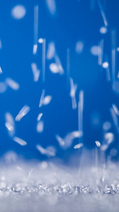 Weiße Superabsorberpolymere, die auf eine Glasoberfläche vor blauem Hintergrund gestreut werden. Weiße Superabsorberpolymere, die auf eine Glasoberfläche vor blauem Hintergrund gestreut werden.