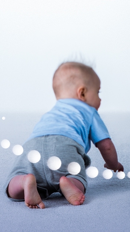 Ein Baby, das neugierig auf einem hellgrauen Teppichboden krabbelt. Ein Baby, das neugierig auf einem hellgrauen Teppichboden krabbelt.