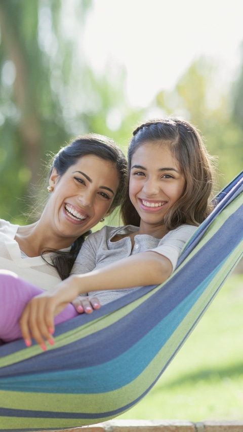 01ANUNFS Portrait of preteen sister and older sister in hammock. 